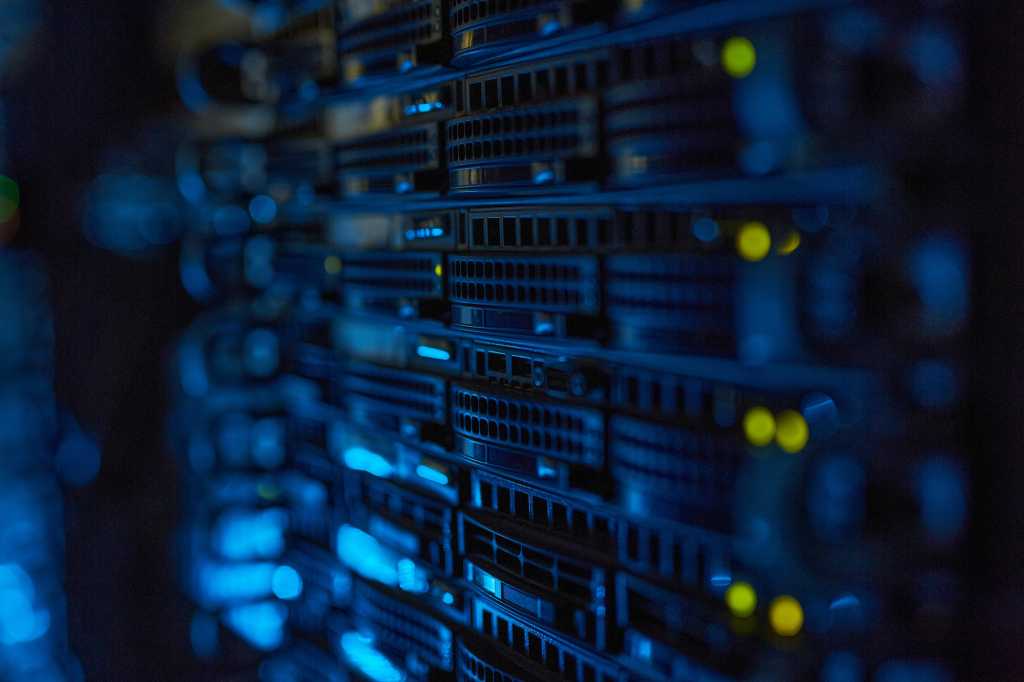 Server racks with illuminated indicators in a dimly lit data center.