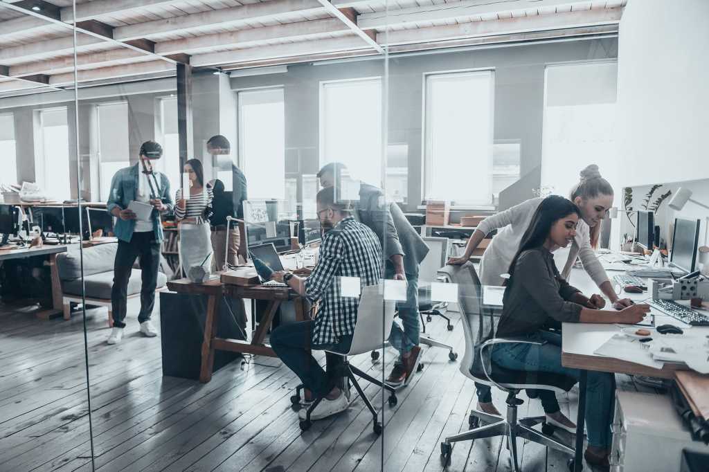 Group of people working together and collaborating in a shared office workspace.