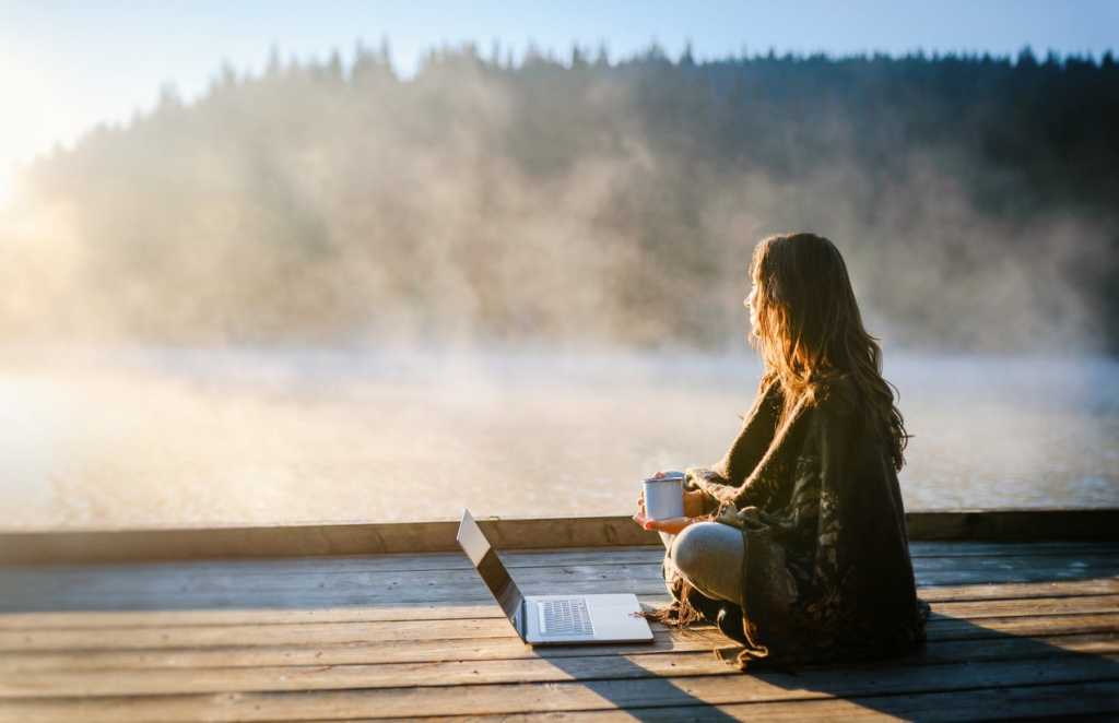 woman looking over lake with laptop